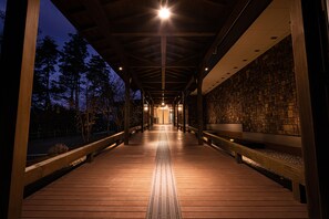 A covered wooden walkway with benches and a stone wall on one side. - The Gran Resort Princess Fujikawaguchiko (Fujikawaguchiko)