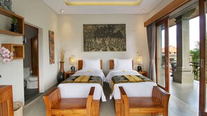 Quarto de hotel com duas camas de madeira, um quadro grande na parede e vista para o exterior através de uma porta de correr.