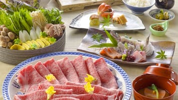 A variety of food items including sashimi, vegetables, and condiments, arranged on a table.
