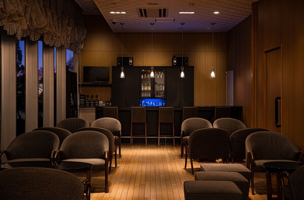 Un espace bar avec des sièges, un comptoir et un écran de télévision.