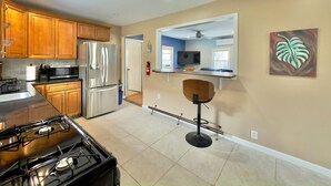 A modern kitchen with stainless steel appliances, wooden cabinets, a gas stove, and a bar stool. - Spring Lake Manor - Rutgers | NYC | Middlesex County New Jersey - EXTENDED STAY (South Plainfield)