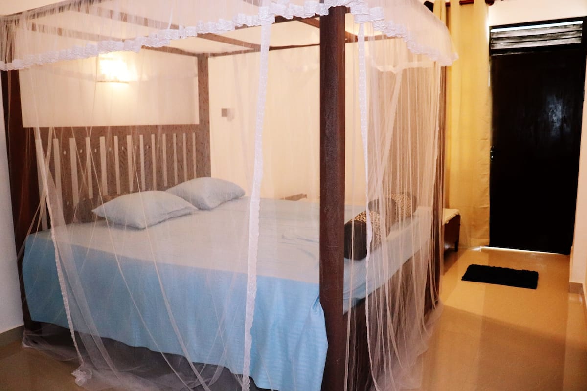 Een bed met hemelbed, een nachtkastje en een nachttafel.