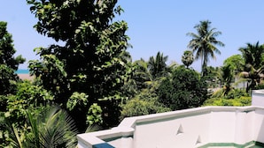 Een wit balkon met uitzicht op weelderige begroeiing en palmbomen.