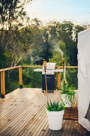 A wooden deck with a barbecue grill and potted plants. - Nature Domes (Toms Creek)