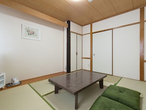 Um quarto japon ês tradicional com piso de tatame, uma mesa de madeira baixa e biombos shoji.