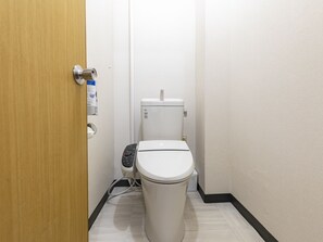 A small, clean bathroom with a toilet, a hand dryer, and a paper towel dispenser. - Tabist Beppu kitahama no yado ao (Beppu)
