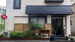A modern two-story building with a black awning, a wooden fence, and potted plants in front. - Tabist Beppu kitahama no yado ao (Beppu)