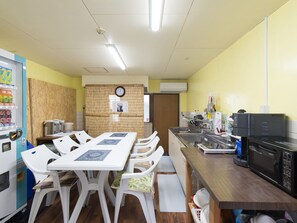 A compact kitchen with a dining table, chairs, a microwave, and a refrigerator. - Tabist Beppu kitahama no yado ao (Beppu)
