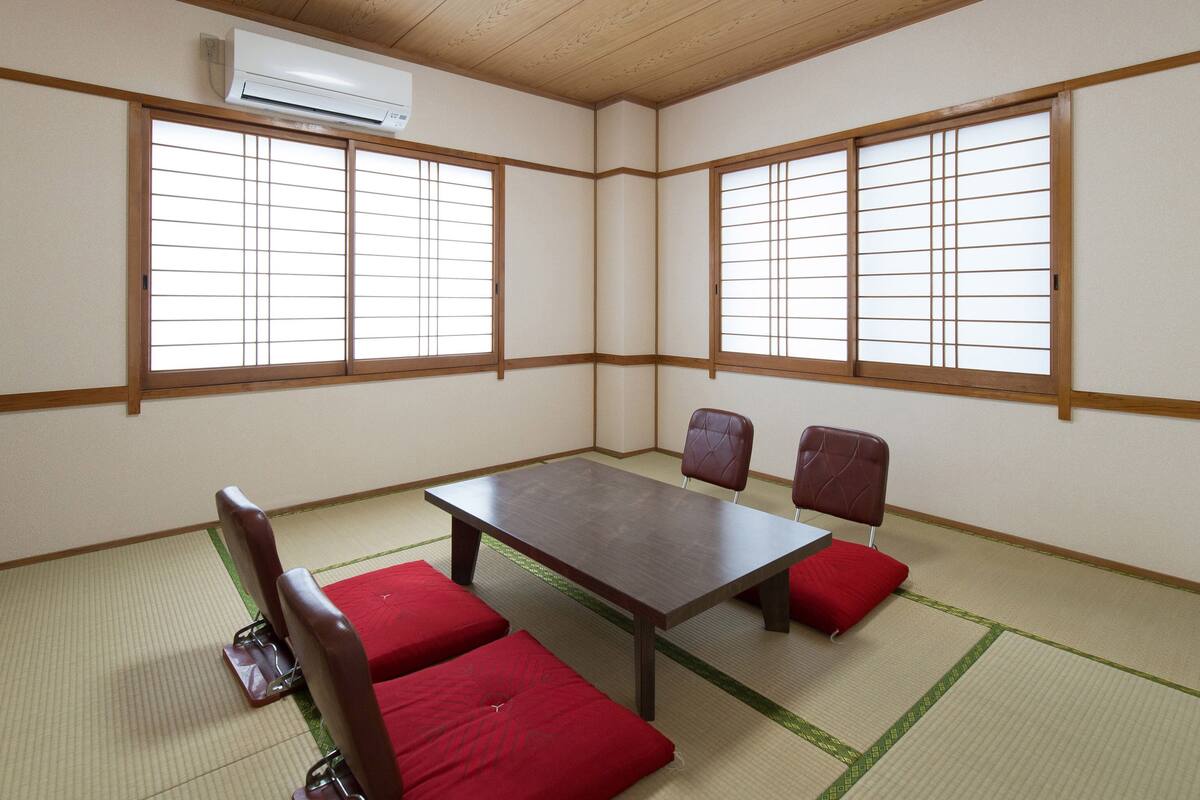Une pièce de style japonais traditionnel, avec un sol recouvert de tatamis, une table basse et deux fauteuils rembourrés.
