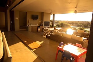 Uma sala moderna com área de jantar, cozinha e uma grande janela com vista para a paisagem.
