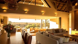 Amplia sala de estar con un sofá grande, mesa de comedor y sillas, con vistas a un paisaje pintoresco.