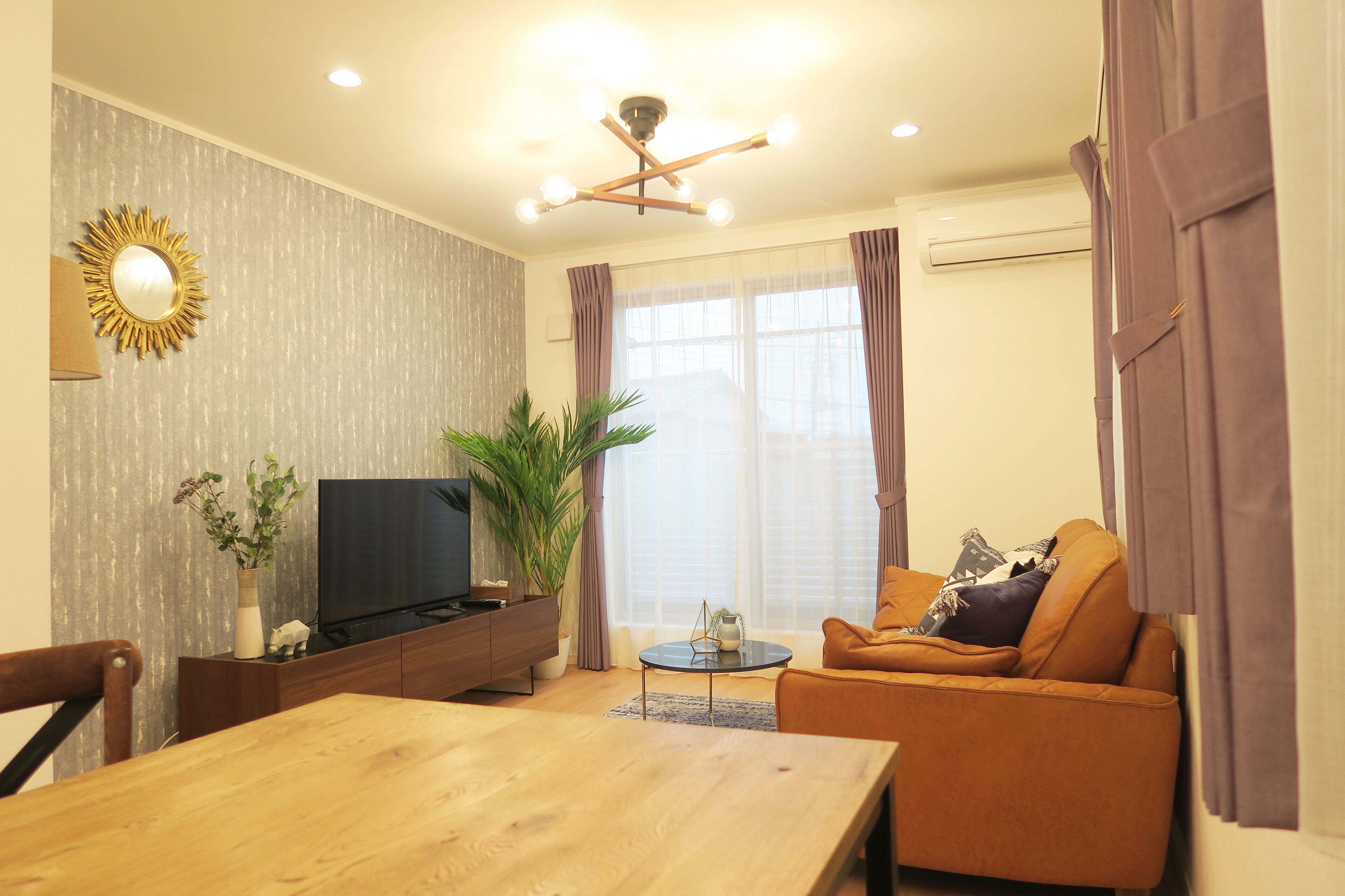 Ein modernes Wohnzimmer mit einem Holzesstisch, einer Couch, einem Fernseher und einem Deckenventilator.