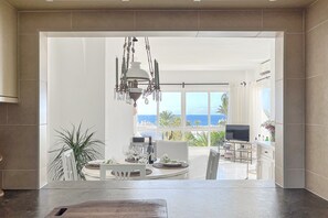 Enjoy ocean views from the dining area, where a chandelier hangs above a table set with white tableware and comfortable chairs.
