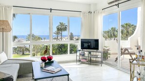 A spacious living room with a large TV, a sofa, and a coffee table. - J07 Jardines 4 - Apartment with sea views (Sitio de Calahonda)