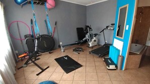 Un gimnasio en casa con equipo de ejercicio, una barra de dominadas y una esterilla de yoga.