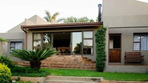 Una casa moderna con un patio, un comedor y una escalera que lleva a la entrada.