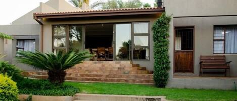 A modern house with a patio, a dining area, and a staircase leading to the entrance.