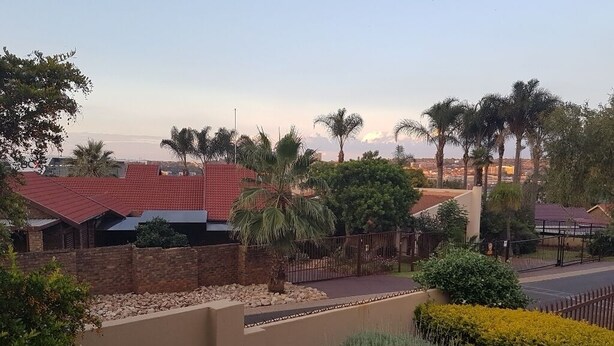 Zona residencial con casas de techo rojo, palmeras y una entrada con portón.