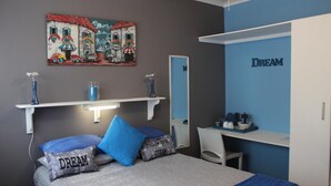 Un dormitorio con cama, escritorio, espejo y una obra de arte en la pared.
