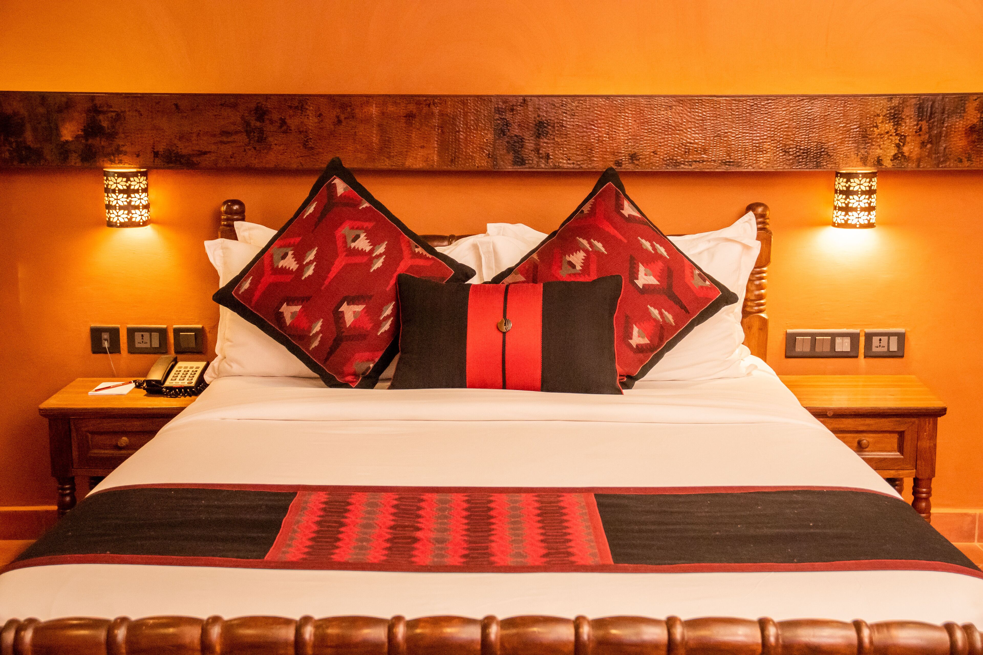 A hotel room with a large bed, two bedside tables, a telephone, and wall-mounted lights.