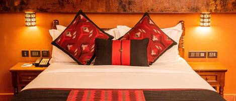 A hotel room with a large bed, two bedside tables, a telephone, and wall-mounted lights.