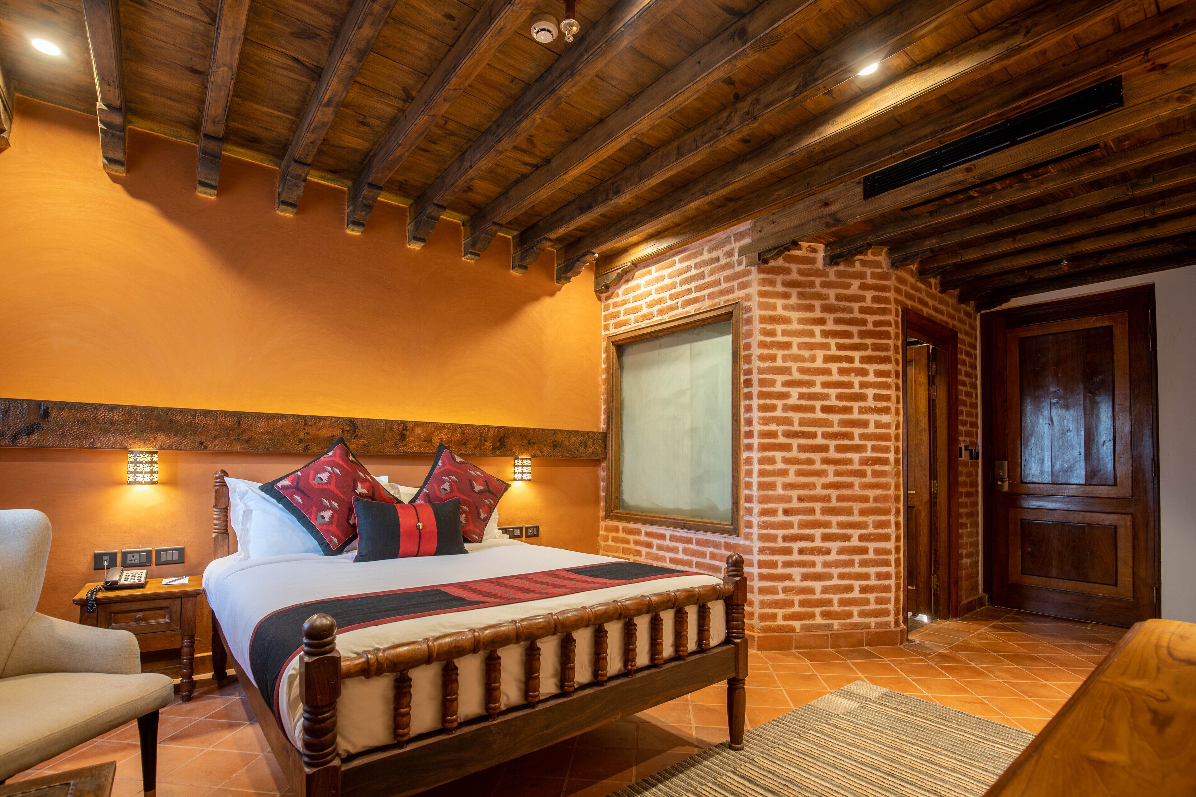 Un dormitorio con cama de madera, pared de ladrillo y un ventanal grande.