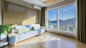 Un salon moderne avec un canapé, une table basse et une grande fenêtre donnant sur la campagne.