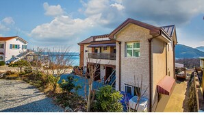 Un immeuble de deux étages avec une façade en pierre, un balcon et une vue sur la mer.