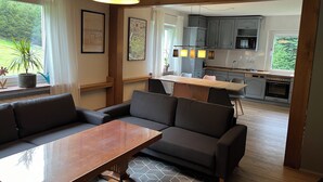 Un salon moderne avec un canapé, une table en bois et une cuisine en arrière-plan.
