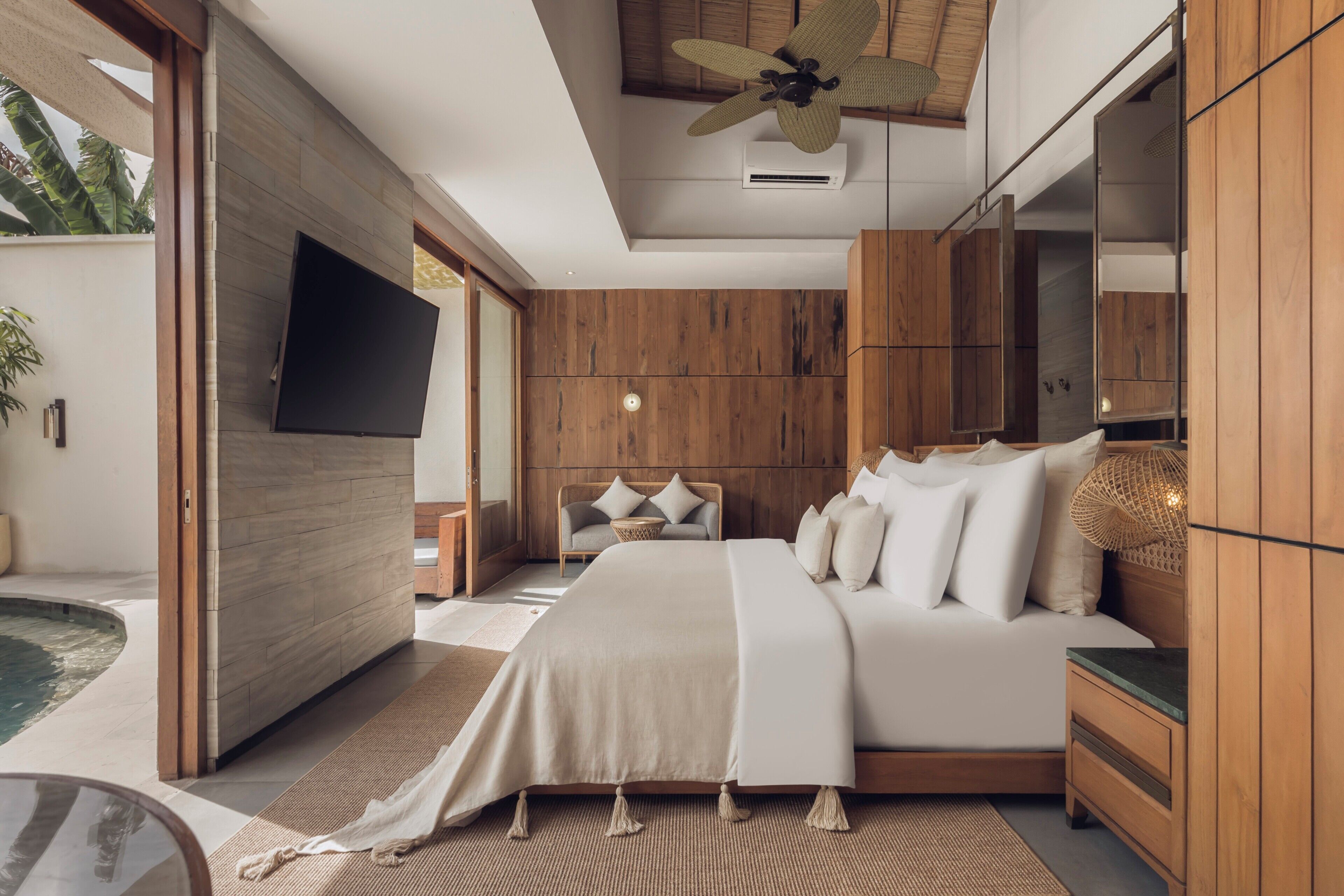 Ein modernes Schlafzimmer mit einem großen Bett, einem Holzschrank und einem an der Wand montierten Fernseher.