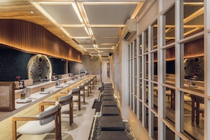 A modern restaurant interior with a long dining table, chairs, and a decorative wall. - Sini Vie Resort & Spa Seminyak by Ini Vie Hospitality (Keroboken Kelod)