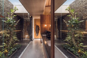 A modern interior with a central wooden wall, glass partitions, and indoor plants. - Sini Vie Resort & Spa Seminyak by Ini Vie Hospitality (Keroboken Kelod)