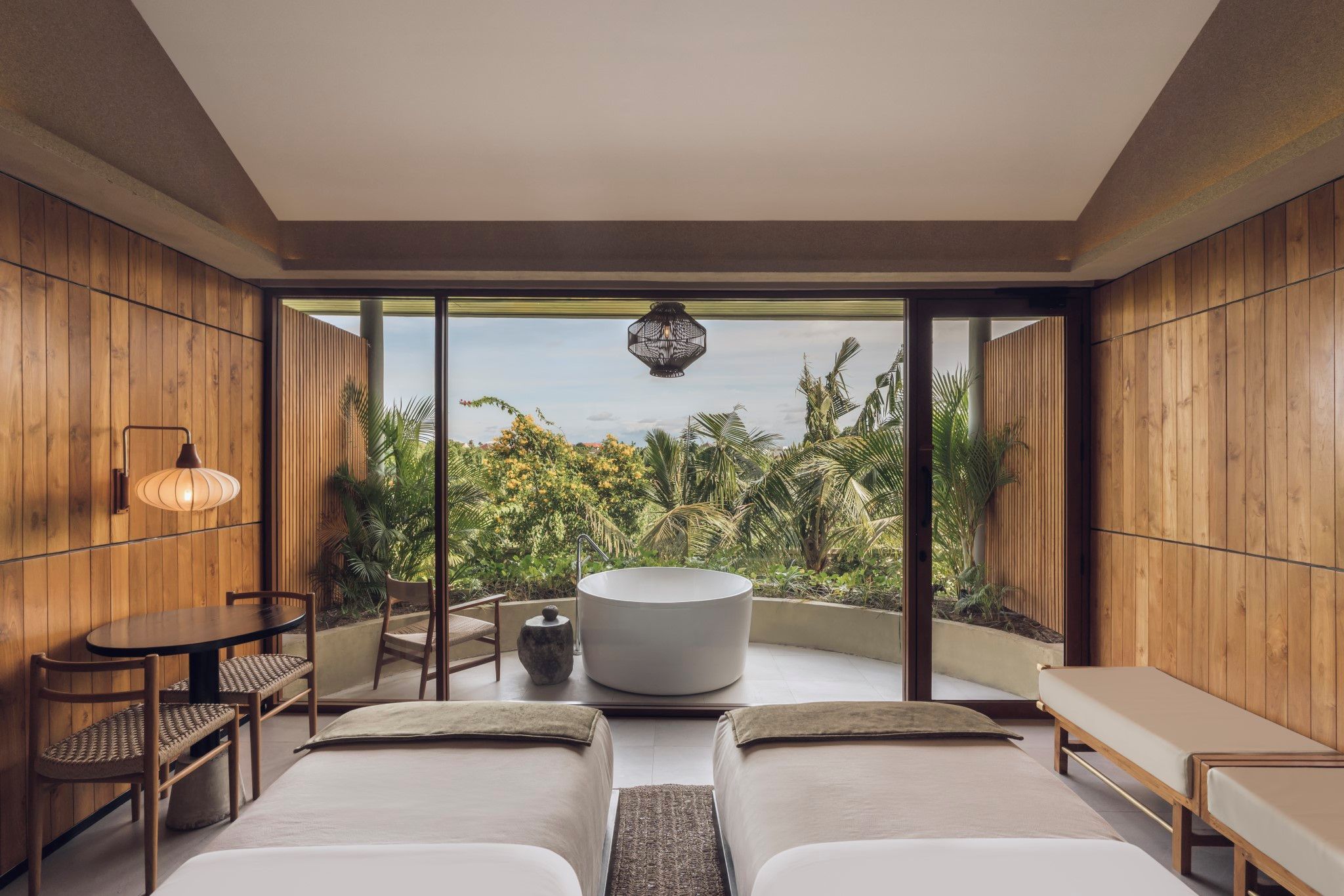 A modern bedroom with a large bed, a round bathtub, and a dining area with chairs and a table.