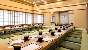 Una habitación tradicional japonesa con suelo de tatami, mesas bajas y puertas correderas shoji.