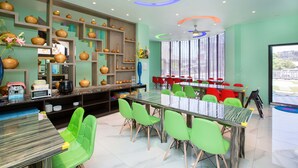 A modern dining area with a glass table, green chairs, and a variety of decorative items on shelves. - Diu Diu Dang Family Homestay (Dongshan)