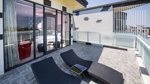 A modern outdoor balcony with glass doors leading to a bedroom, furnished with two lounge chairs and a small table. - Diu Diu Dang Family Homestay (Dongshan)