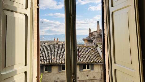 An open door revealing a view of traditional buildings with tiled roofs and a clear sky. - Mavitur Rooms (Assisi)