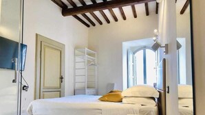 A bedroom with a bed, a wardrobe, a mirror, and a window. - Mavitur Rooms (Assisi)