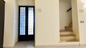 A hallway with two arched doorways leading to a staircase and a door with a frosted glass window. - Mavitur Rooms (Assisi)