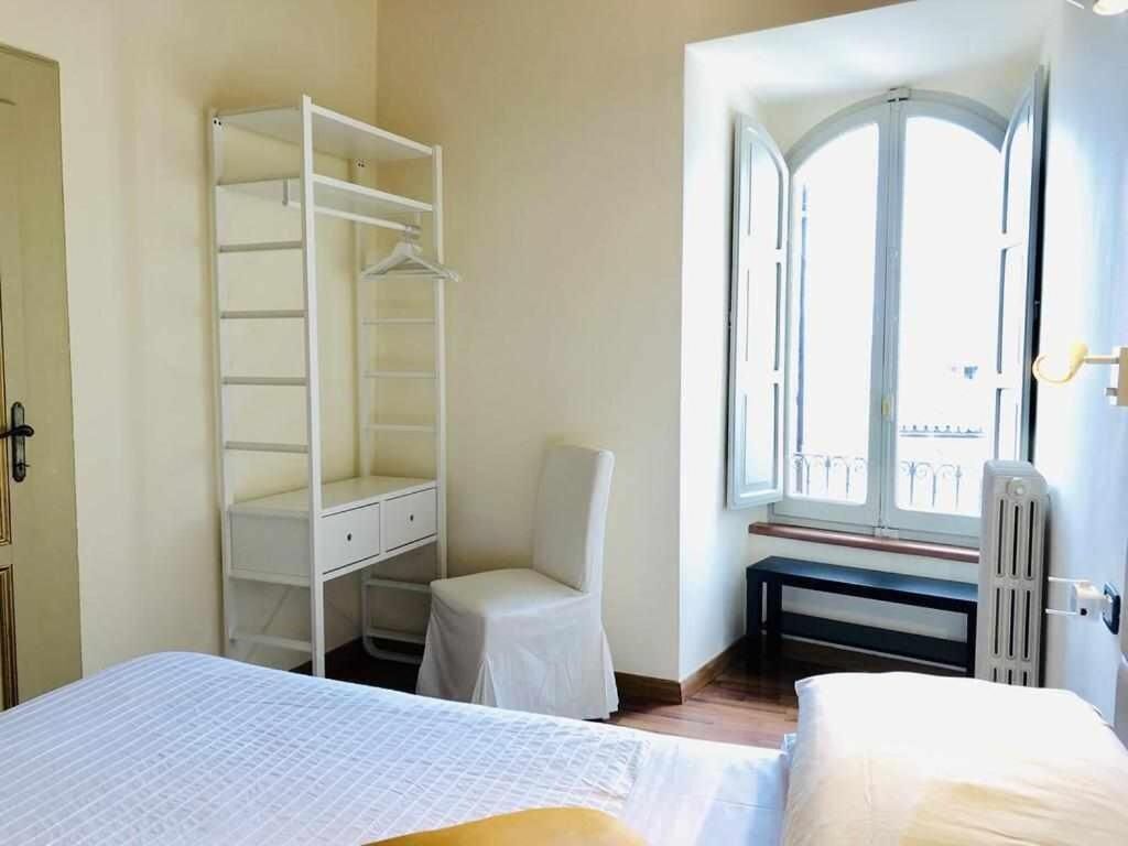 Un dormitorio con cama, un armario blanco, una silla y una ventana con vistas.