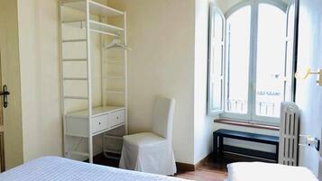 Un dormitorio con cama, un armario blanco, una silla y una ventana con vistas.