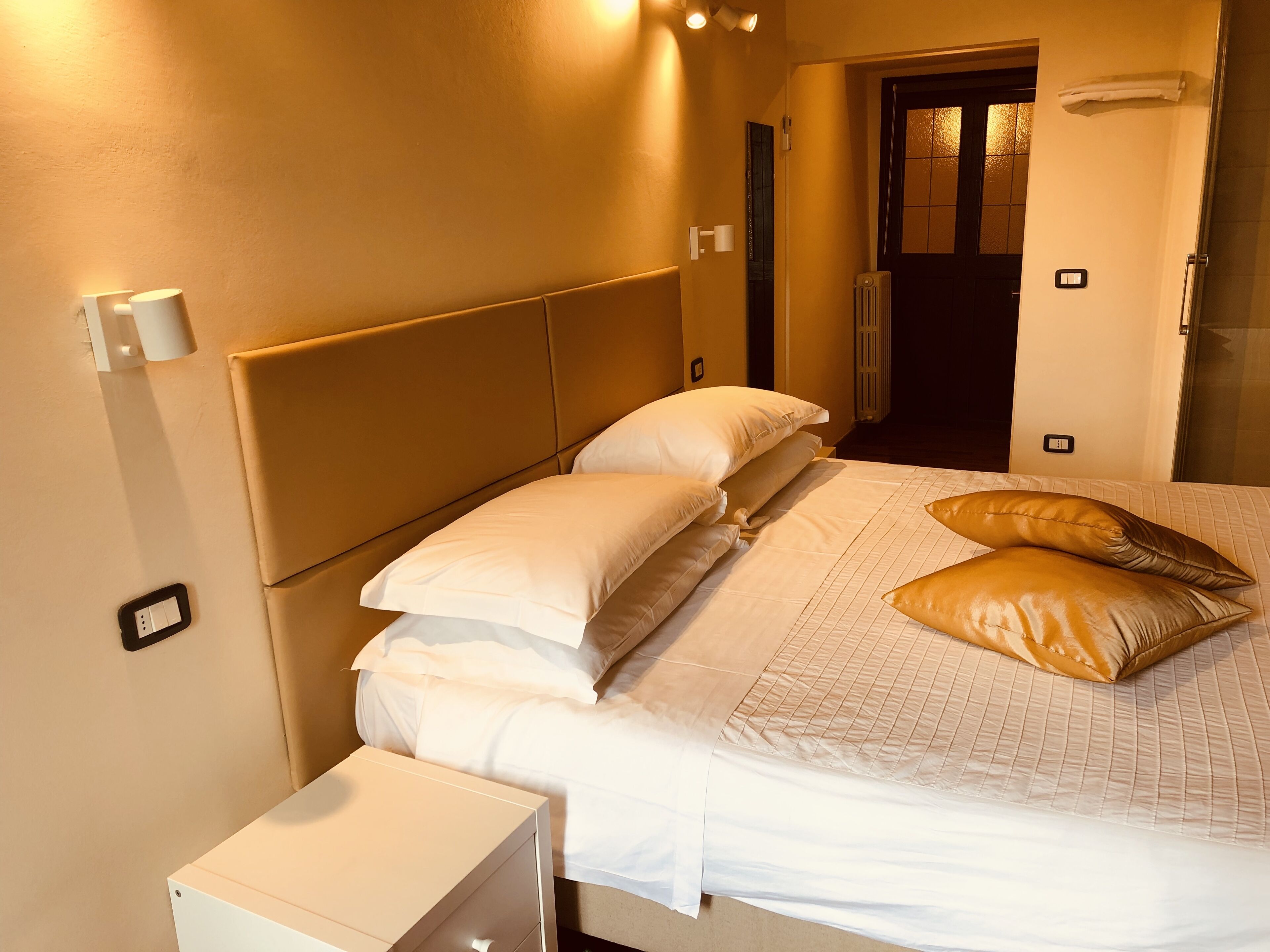 A hotel room with a bed, bedside table, and a door leading to a bathroom.
