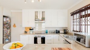 A modern kitchen with white cabinets, a built-in oven, and a sink. - Nansen Place (Cape Town)
