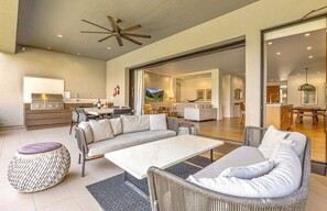 A spacious living area with a large sofa, a dining table, and a kitchen area with a grill. - Maui Resort Rentals: 6 Total Bedrooms at Kaanapali’s Newest Luxury Residences, Steps from Beach & Resort Amenities! (Lahaina)