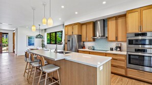 Eine moderne Küche mit Holzausstattung, Edelstahlgeräten und einer zentralen Kochinsel mit Barhocker.