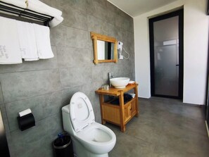 A modern bathroom with a white toilet, a wooden vanity with a sink, and a mirror above the vanity.