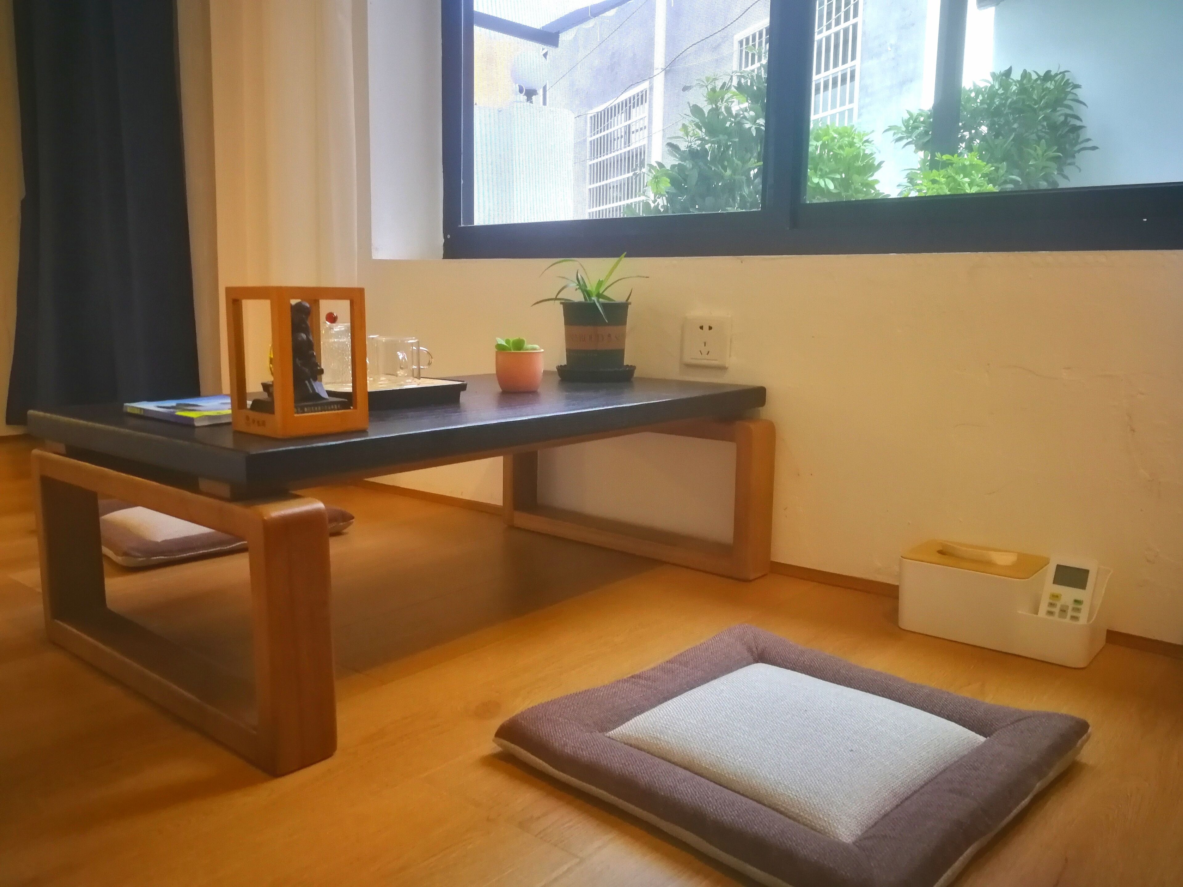 A room with a wooden desk, a small potted plant, a framed picture, and a pet bed.