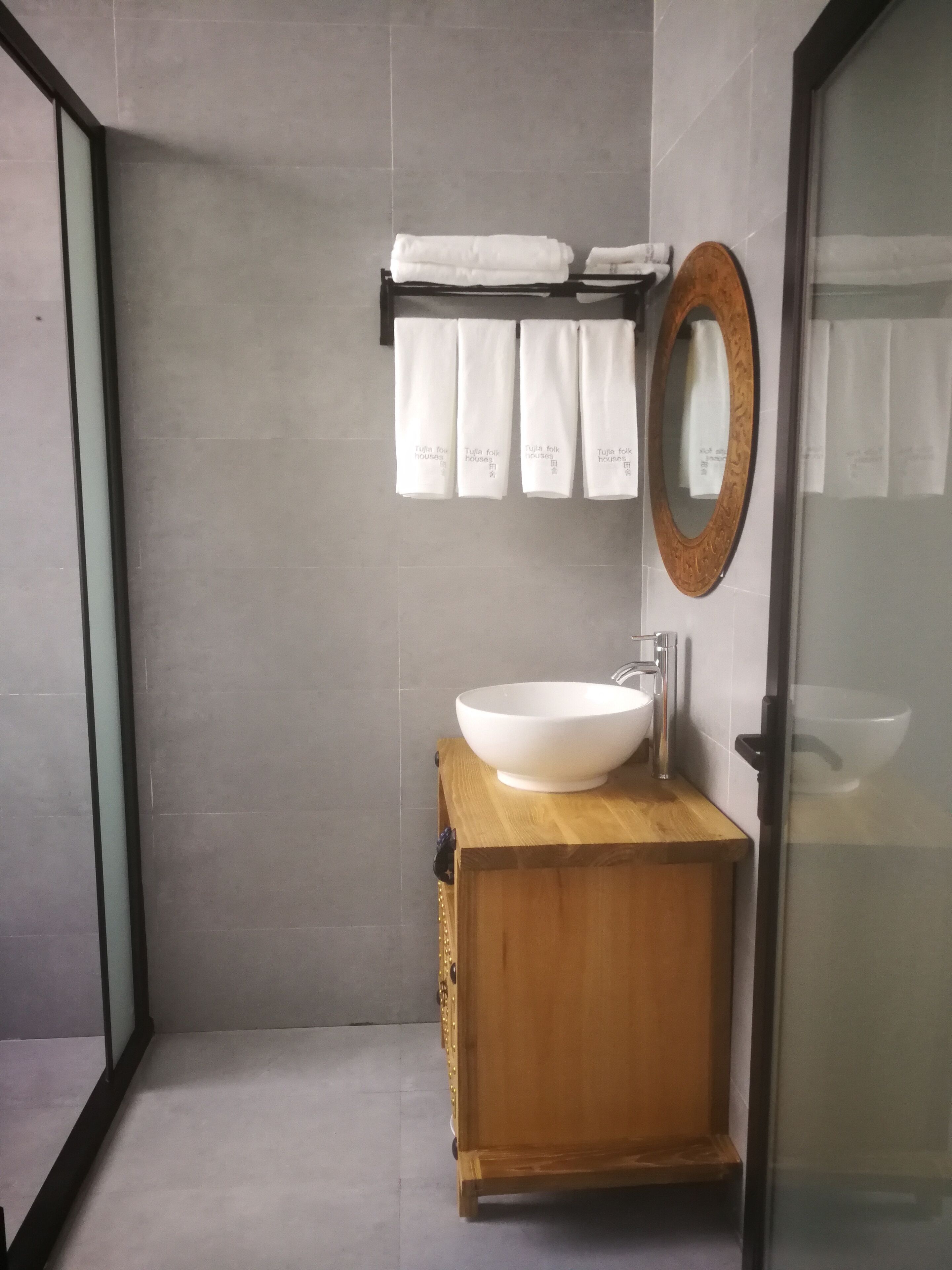 A modern bathroom with a large white sink, wooden vanity, and a mirror with a decorative frame.