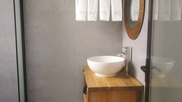 A modern bathroom with a large white sink, wooden vanity, and a mirror with a decorative frame.