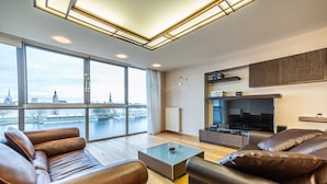 Een moderne woonkamer met leren banken, een glazen salontafel en een grote televisie.